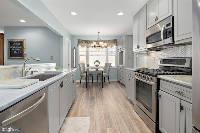 352 Ocean, Ocean Pines, MD 21811 - kitchen featuring appliances with stainless steel finishes, a chandelier, decorative backsplash, light countertops, and light wood-style floors