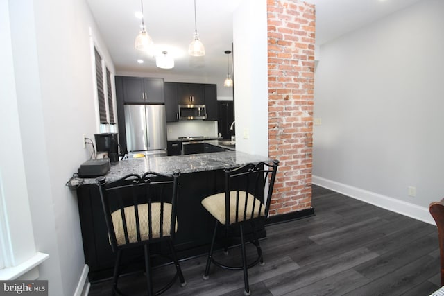 126 E Third St, Lansdale, PA 19446 - kitchen with stainless steel appliances, dark wood-style floors, dark stone countertops, a peninsula, and a breakfast bar