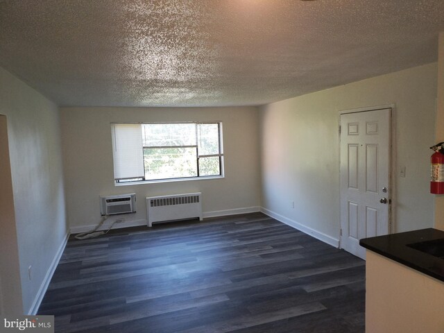 4715 1st St SW, Washington, DC 20032 - unfurnished living room with radiator heating unit, a textured ceiling, dark wood-style floors, and an AC wall unit