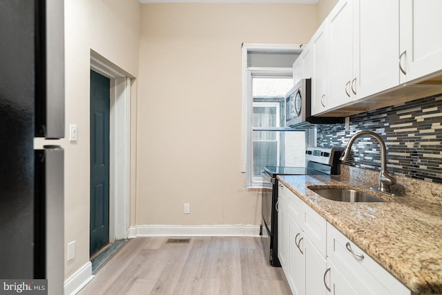 4136 Pennsgrove St, Philadelphia, PA 19104 - kitchen with stainless steel appliances, light wood-type flooring, tasteful backsplash, white cabinets, and light stone countertops
