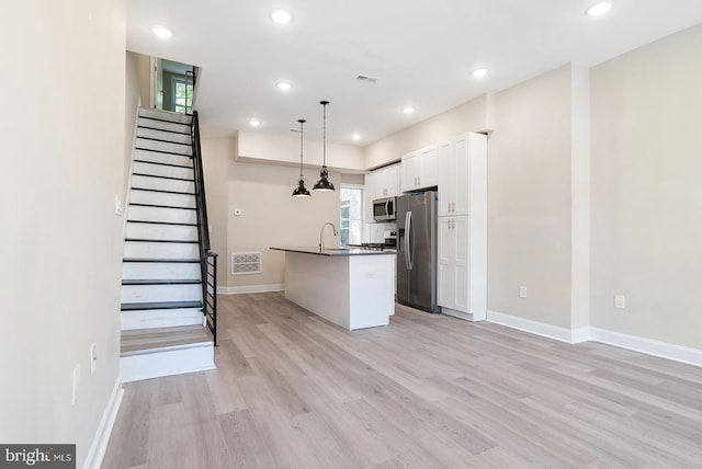 4136 Pennsgrove St, Philadelphia, PA 19104 - kitchen featuring stainless steel appliances, dark countertops, light wood-style flooring, white cabinets, and recessed lighting