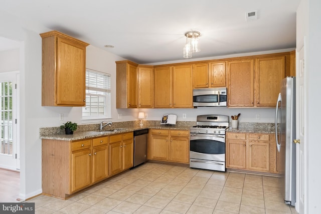 14608 Turara Ct, Haymarket, VA 20169 - kitchen with stainless steel appliances, stone counters, light tile patterned floors, and brown cabinets