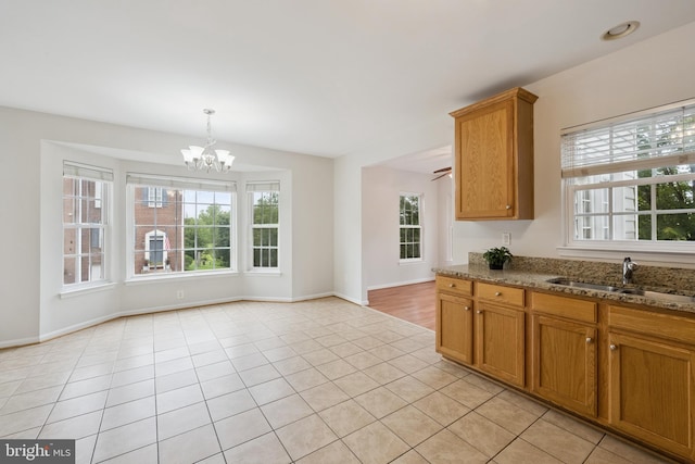 14608 Turara Ct, Haymarket, VA 20169 - kitchen with a chandelier, stone countertops, brown cabinets, hanging light fixtures, and light tile patterned floors