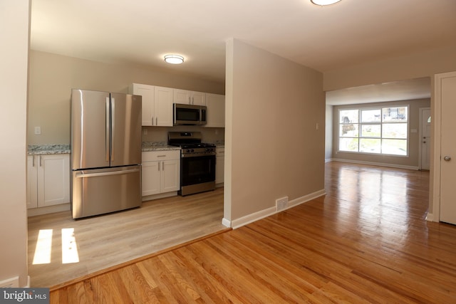 607 Briarcliff Rd, Upper Darby, PA 19082 - kitchen with appliances with stainless steel finishes, light wood-style flooring, white cabinets, and light stone countertops