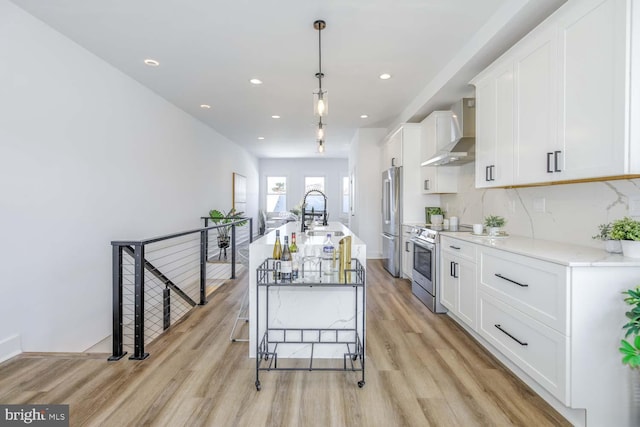 424 Taylor St NW Unit B, Washington, DC 20011 - kitchen featuring wall chimney range hood, appliances with stainless steel finishes, light wood-style flooring, white cabinets, and recessed lighting