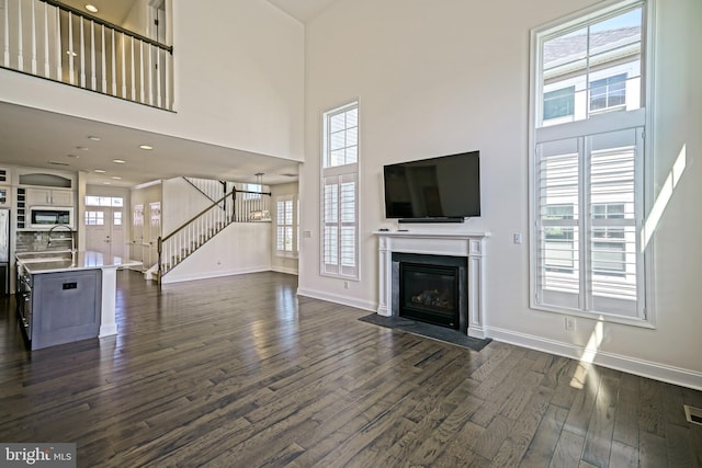 11454 Maull Rd, Lewes, DE 19958 - unfurnished living room featuring a high ceiling, dark wood-type flooring, stairway, and a fireplace with flush hearth