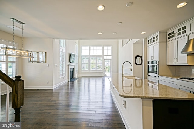 11454 Maull Rd, Lewes, DE 19958 - kitchen with stainless steel oven, an island with sink, dark wood-style flooring, gas cooktop, and healthy amount of natural light