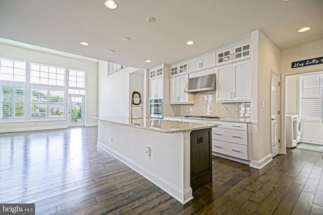 11454 Maull Rd, Lewes, DE 19958 - kitchen featuring wall chimney range hood, washing machine and clothes dryer, dark wood-style flooring, gas cooktop, and stainless steel oven