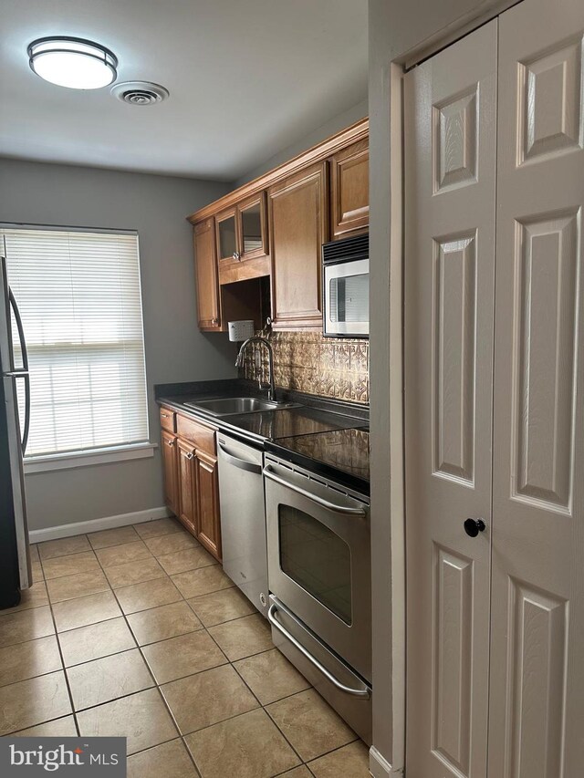 400 Calburn Ct, Bear, DE 19701 - kitchen featuring stainless steel appliances, light tile patterned flooring, dark countertops, brown cabinets, and glass insert cabinets