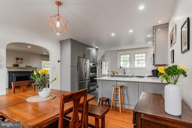 2416 Whitby Rd, Havertown, PA 19083 - dining room featuring arched walkways, recessed lighting, a fireplace, light wood-type flooring, and lofted ceiling