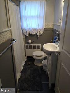 310 Crest Dr, Clarks Green, PA 18411 - full bathroom featuring radiator heating unit, vanity, a shower with curtain, and tile patterned flooring