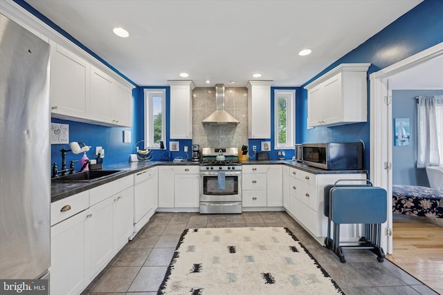 39 E 2nd Ave, Runnemede, NJ 08078 - kitchen featuring appliances with stainless steel finishes, wall chimney exhaust hood, dark countertops, white cabinetry, and light tile patterned flooring