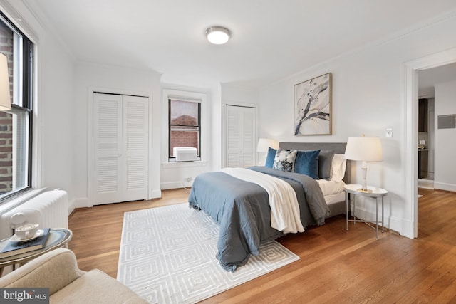 1915 16th St NW Unit 203, Washington, DC 20009 - bedroom with two closets, ornamental molding, wood finished floors, and radiator heating unit