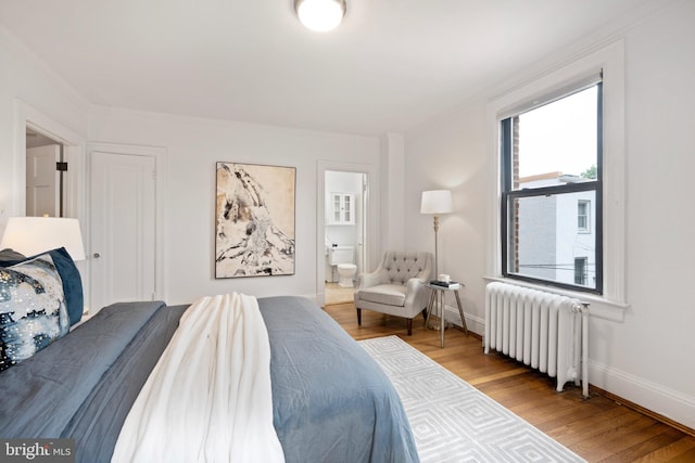 1915 16th St NW Unit 203, Washington, DC 20009 - bedroom with radiator heating unit, wood finished floors, crown molding, and connected bathroom