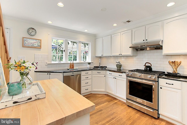 3132 Holmes Run Rd, Falls Church, VA 22042 - kitchen with stainless steel appliances, under cabinet range hood, ornamental molding, white cabinetry, and tasteful backsplash