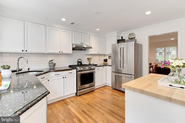 3132 Holmes Run Rd, Falls Church, VA 22042 - kitchen with stainless steel appliances, under cabinet range hood, light wood-type flooring, white cabinets, and decorative backsplash