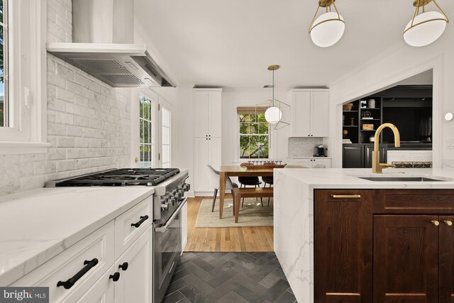 110 E Nelson Ave, Alexandria, VA 22301 - kitchen featuring stainless steel stove, wall chimney exhaust hood, backsplash, white cabinetry, and healthy amount of natural light