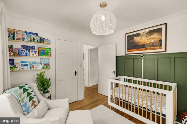 110 E Nelson Ave, Alexandria, VA 22301 - bedroom featuring ornamental molding, wood finished floors, a nursery area, wainscoting, and a decorative wall