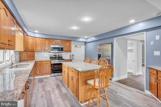 324 W Clayton Ave, Clayton, NJ 08312 - kitchen featuring appliances with stainless steel finishes, a breakfast bar, light wood finished floors, decorative backsplash, and light stone counters