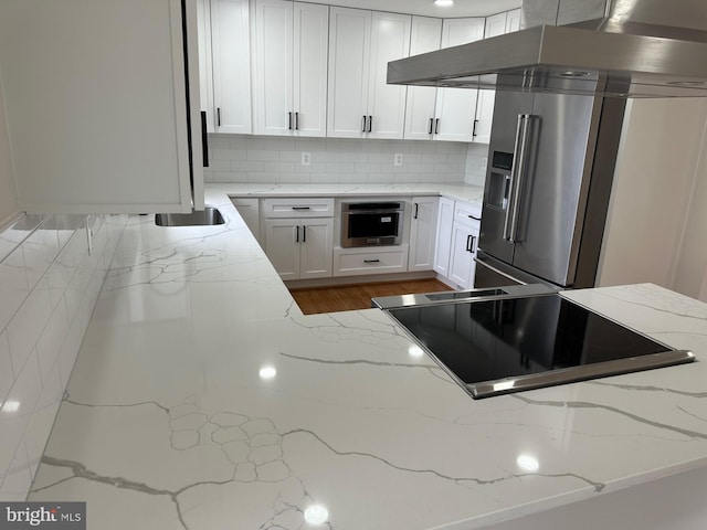 6087 8th Pl N, Arlington, VA 22205 - kitchen featuring wall chimney exhaust hood, appliances with stainless steel finishes, white cabinets, backsplash, and light stone counters