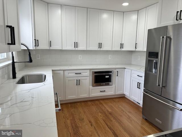 6087 8th Pl N, Arlington, VA 22205 - kitchen with high quality fridge, white cabinetry, backsplash, light wood finished floors, and light stone counters