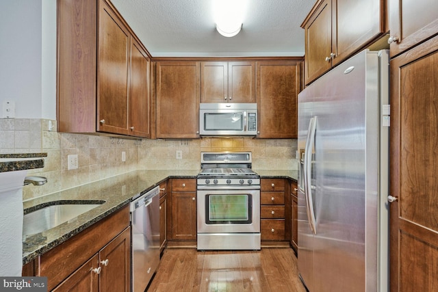 11750 Old Georgetown Unit 2524, Rockville, MD 20852 - kitchen featuring stainless steel appliances, dark stone countertops, light wood-style floors, brown cabinets, and backsplash