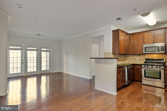 11750 Old Georgetown Unit 2524, Rockville, MD 20852 - kitchen featuring appliances with stainless steel finishes, wood finished floors, decorative backsplash, crown molding, and open floor plan