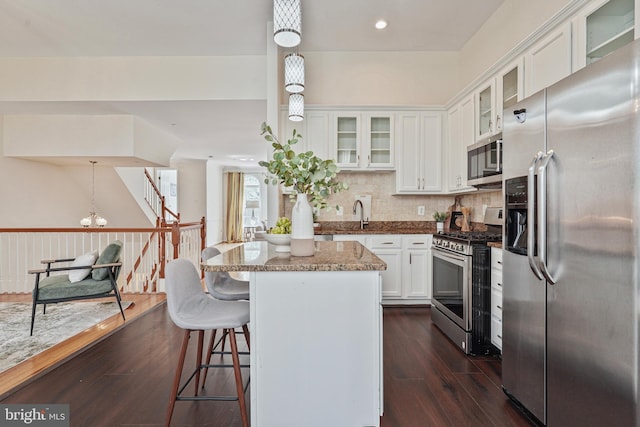 440 Clayton Ln, Alexandria, VA 22304 - kitchen featuring appliances with stainless steel finishes, a kitchen island, white cabinetry, dark wood-style flooring, and a breakfast bar