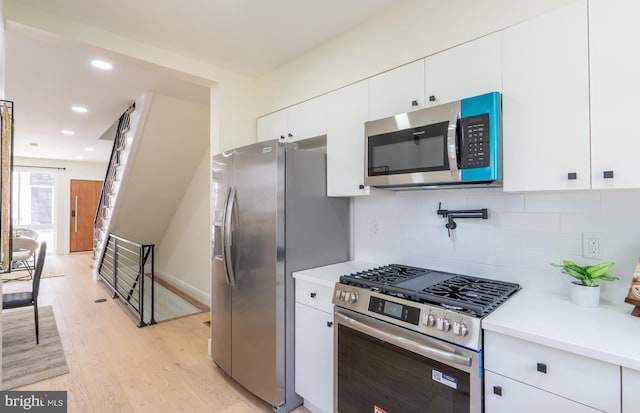 622 Mcclellan St, Philadelphia, PA 19148 - kitchen featuring appliances with stainless steel finishes, light wood-style flooring, light countertops, backsplash, and white cabinetry