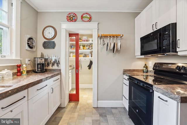 4009 Oglethorpe St, Hyattsville, MD 20782 - kitchen featuring black appliances, white cabinets, stone finish floors, dark countertops, and ornamental molding