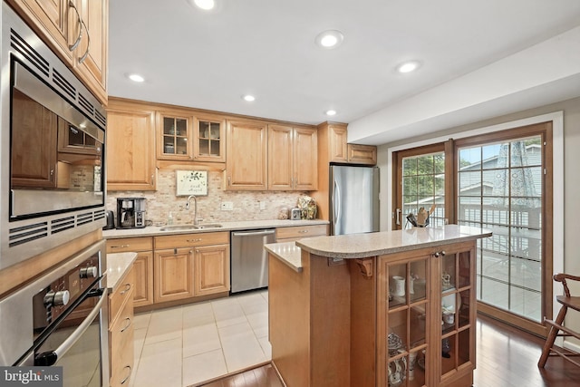 8823 Newport Ct, Springfield, VA 22153 - kitchen with appliances with stainless steel finishes, backsplash, glass insert cabinets, a center island, and light brown cabinets