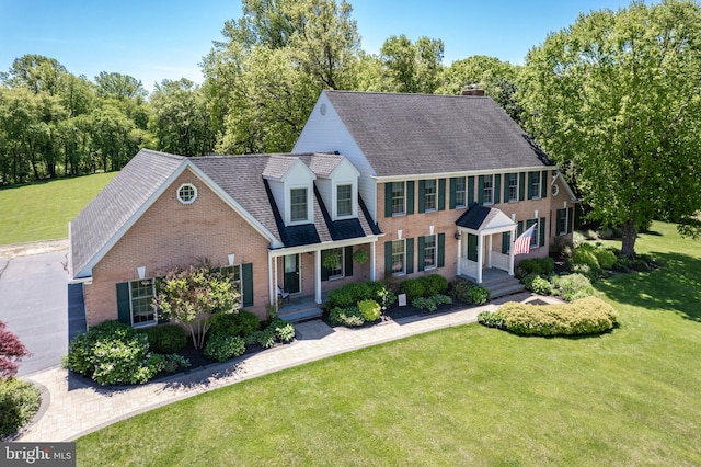 872 The Old Station Ct, Woodbine, MD 21797 - view of front of home featuring brick siding, a front yard, a shingled roof, and a chimney
