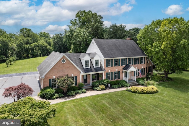 872 The Old Station Ct, Woodbine, MD 21797 - view of front of home featuring brick siding, a front lawn, roof with shingles, a chimney, and a porch