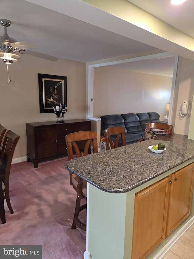 6132 Charles St, Philadelphia, PA 19135 - kitchen with carpet floors, dark stone counters, a ceiling fan, open floor plan, and a kitchen breakfast bar