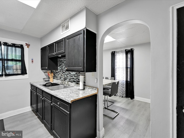 332 W Maple St, York, PA 17401 - kitchen featuring dark cabinetry, arched walkways, light wood-type flooring, light countertops, and a paneled ceiling