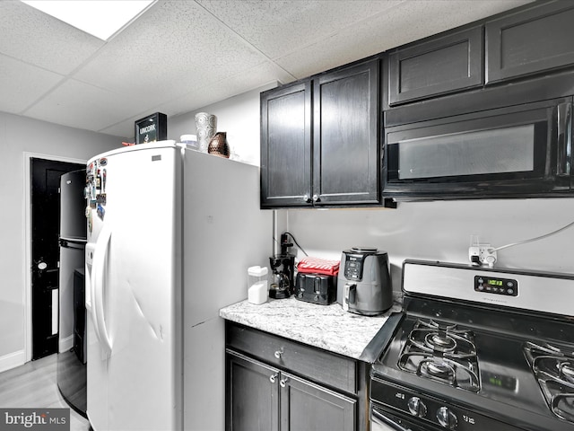 332 W Maple St, York, PA 17401 - kitchen with gas stove, black microwave, white refrigerator with ice dispenser, a drop ceiling, and light wood-style floors