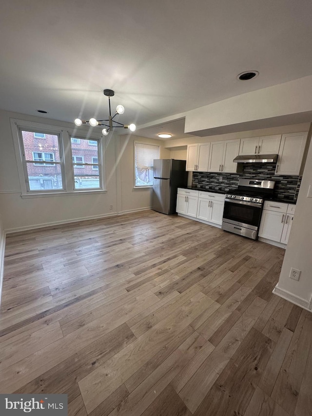 7269 Rutland St, Philadelphia, PA 19149 - kitchen with appliances with stainless steel finishes, a chandelier, light wood-style flooring, backsplash, and under cabinet range hood