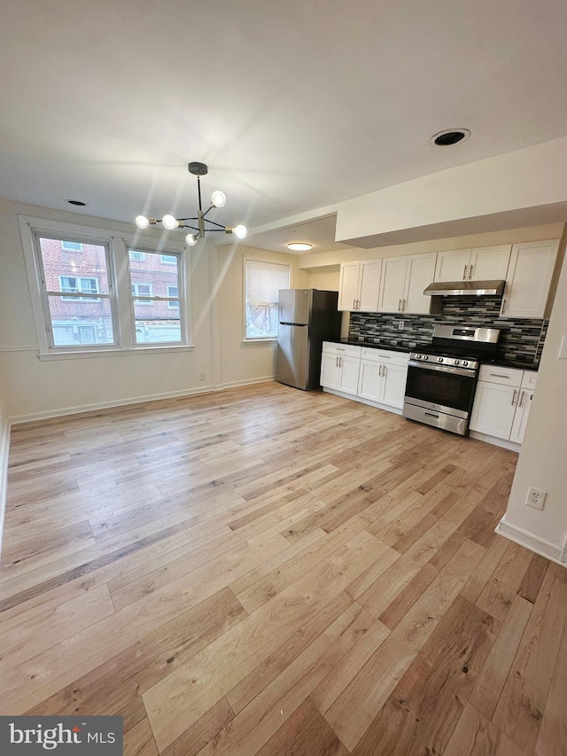 7269 Rutland St, Philadelphia, PA 19149 - kitchen featuring stainless steel appliances, light wood-style floors, a chandelier, tasteful backsplash, and dark countertops
