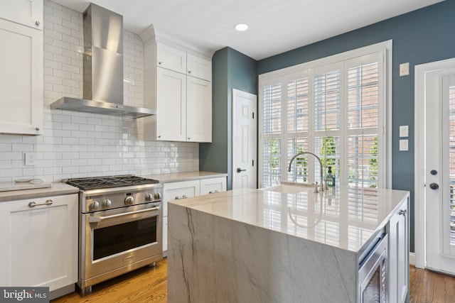 1206 N Pitt St, Alexandria, VA 22314 - kitchen with high end stove, wall chimney exhaust hood, light wood-style floors, tasteful backsplash, and white cabinetry