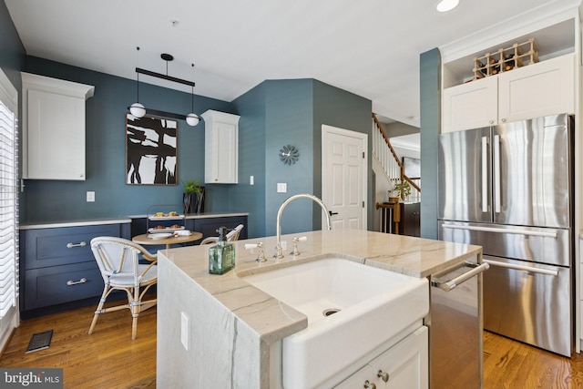 1206 N Pitt St, Alexandria, VA 22314 - kitchen featuring appliances with stainless steel finishes, white cabinetry, light wood-style floors, light stone counters, and pendant lighting