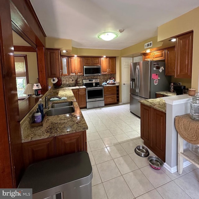 82 Blue Fox Ln, Richboro, PA 18954 - kitchen with appliances with stainless steel finishes, decorative backsplash, brown cabinets, light tile patterned floors, and light stone counters