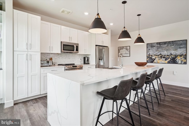 1761 Old Meadow Rd Unit 412, Mclean, VA 22102 - kitchen with appliances with stainless steel finishes, dark wood-style floors, a center island with sink, backsplash, and white cabinetry