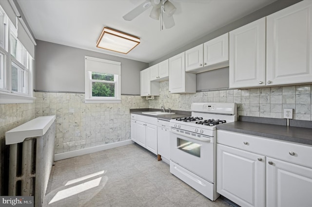 445 Dupont St, Philadelphia, PA 19128 - kitchen with white gas stove, dark countertops, white cabinets, wainscoting, and a ceiling fan