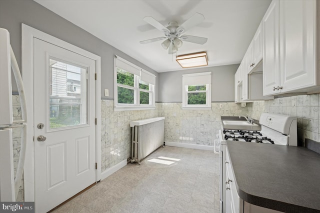 445 Dupont St, Philadelphia, PA 19128 - kitchen with white appliances, dark countertops, a ceiling fan, white cabinets, and tile walls