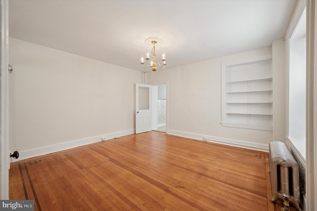 445 Dupont St, Philadelphia, PA 19128 - spare room featuring radiator, a chandelier, built in shelves, and wood finished floors