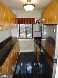 3901 Tunlaw Rd NW Unit 202, Washington, DC 20007 - kitchen with freestanding refrigerator, granite floors, dark countertops, and brown cabinetry