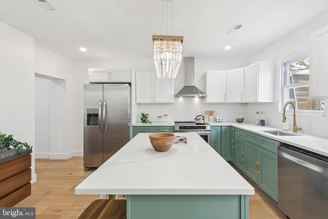 1232 S Bucknell St, Philadelphia, PA 19146 - kitchen featuring stainless steel appliances, wall chimney range hood, green cabinets, light wood-type flooring, and decorative backsplash