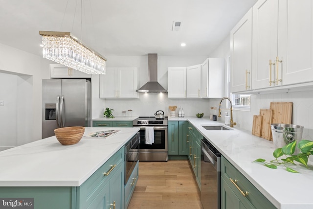 1232 S Bucknell St, Philadelphia, PA 19146 - kitchen with stainless steel appliances, wall chimney range hood, green cabinetry, white cabinetry, and light wood-type flooring