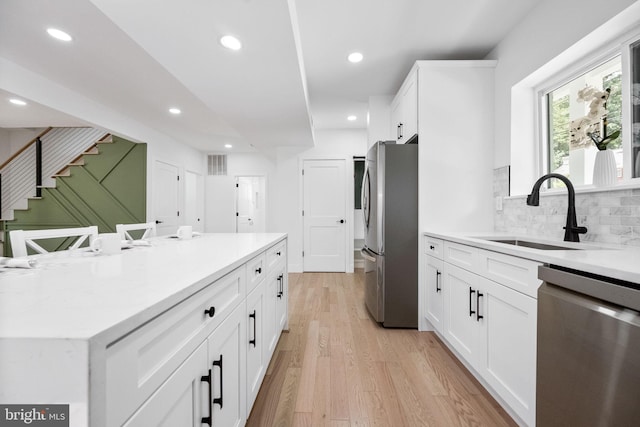 7214 16th Ave, Takoma Park, MD 20912 - kitchen featuring stainless steel appliances, white cabinets, tasteful backsplash, light wood-style floors, and recessed lighting