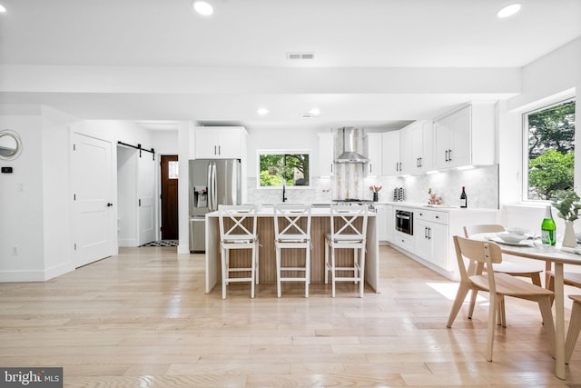 7214 16th Ave, Takoma Park, MD 20912 - kitchen with a barn door, a kitchen island, wall chimney range hood, stainless steel appliances, and recessed lighting